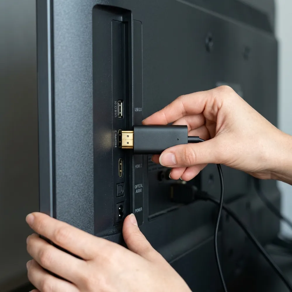 Hands plugging USA EZStream stick into television HDMI port